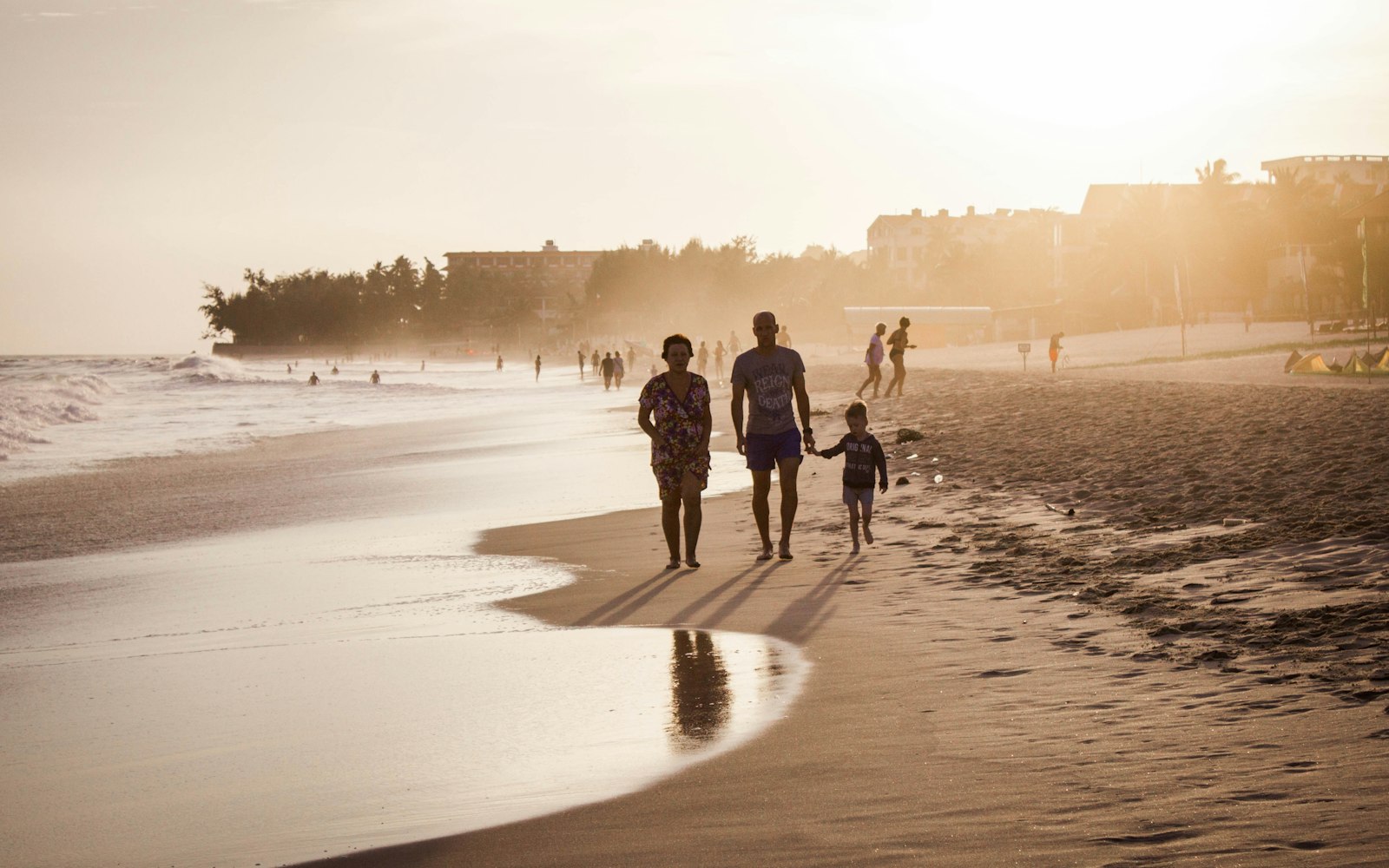 Family walking along a Sunshine Coast beach at sunset