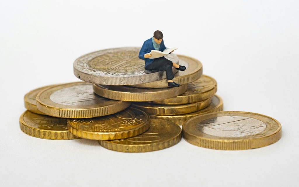Miniature figure sitting on a stack of coins