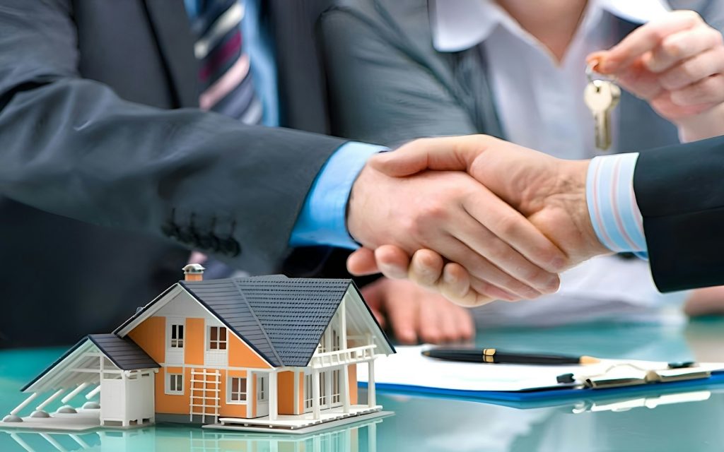 Two people shaking hands over a model house